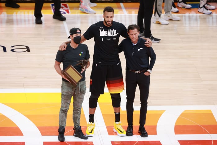 Rudy Gobert (center) is awarded the Defensive Player of the Year Award by Jazz Owner Ryan Smith (left) and Head Coach Quin Snyder (right)
